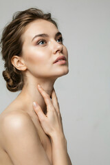 Fototapeta premium Woman touching neck, looking up with serene expression.