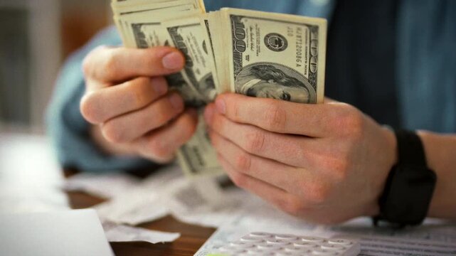 Accountant sits at a table, counting cash while consulting documents and a calculator, meticulously processing payroll for a small-business workforce, ensuring accurate wages and financial compliance