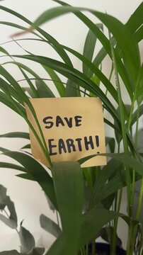 Save earth sticky note among green palm leaves environmental message