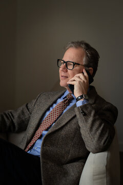 Mature businessman talking on mobile phone while sitting in hotel room