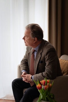 Thoughtful mature businessman looking through window in hotel room