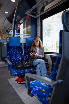 Mature businesswoman using smartphone while traveling by train