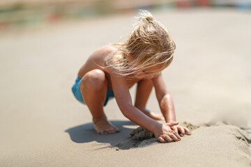 Fototapeta premium Toddler Building Sandcastle At Beach