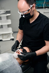 Focused male dentist performing procedure on patient in clinic