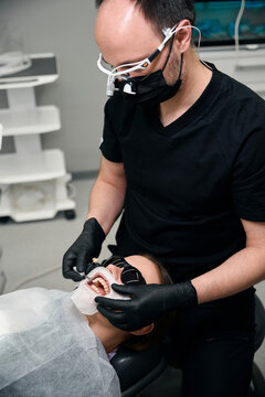 Focused male dentist performing procedure on patient in clinic