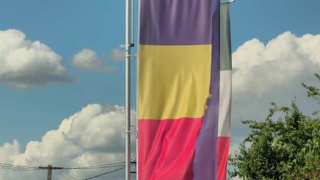 Romanian and European Union (EU) and Italian flags blowing in the wind on a sunny day