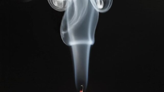 Candle smoke trail moves upward on a black background showing patterns and shapes