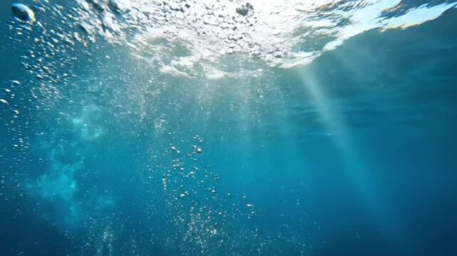 Underwater view of air bubbles rising in clear water with light shining from above