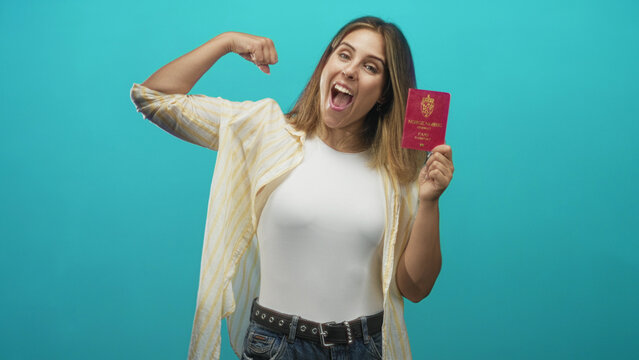 Young hispanic woman flexes bicep and holds norwegian passport against turquoise backdrop in studio, open mouth smile; pride travel.