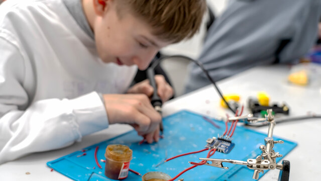 Young boy concentrates on soldering electronic components