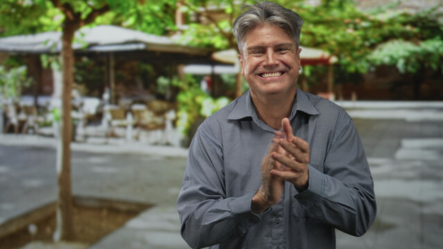 Man clapping hands at outdoor street cafe terrace, smiling with grey hair in a button shirt, facing camera and applauding in several repeated frames; celebration joy.