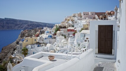 Fototapeta premium White cliffside buildings and blue domes seen with soft shallow bokeh background, sunlit coastal scene; background backplate copyspace calm.