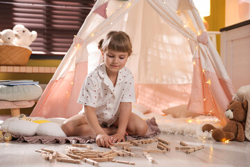 Little girl playing with building blocks in wigwam at home © New Africa