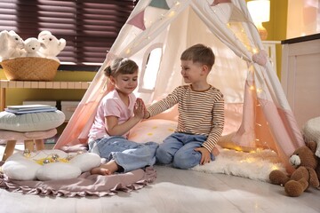 Little girl and boy playing in wigwam at home © New Africa