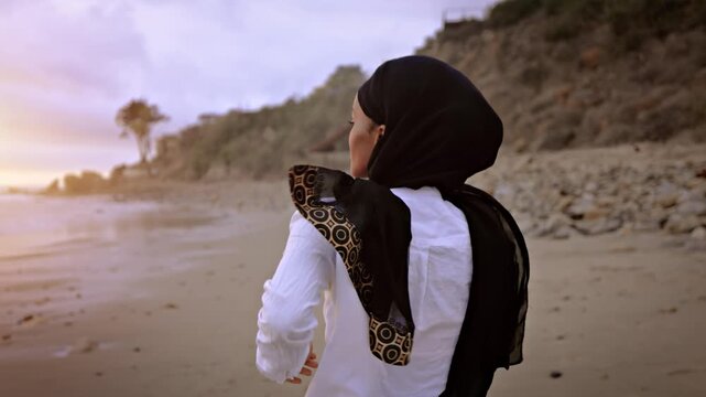 Somali-American woman jogging on the beach in Malibu at sunset.