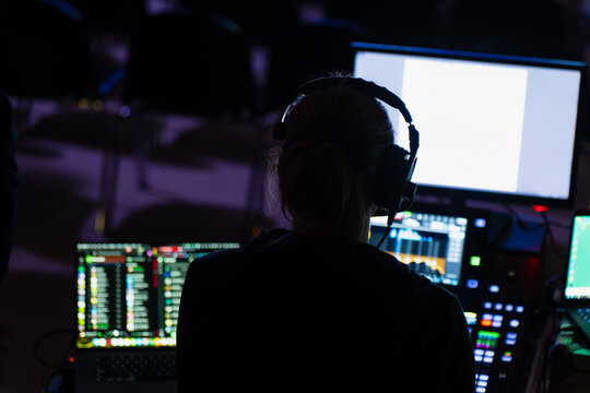 An audio visual specialist monitors multi screen production software on an interactive display terminal inside a tech control room venue station