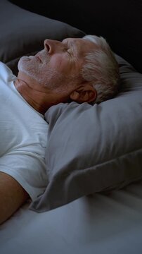 Mature adult sleeping at night. Vertical Video.