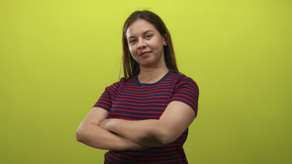 Obraz premium Woman with arms crossed and a thumbs up gesture in a studio with lime green backdrop; confidence approval.