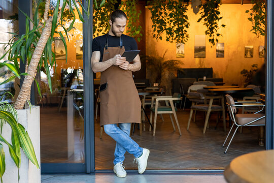 Full length portrait of waiter with tablet