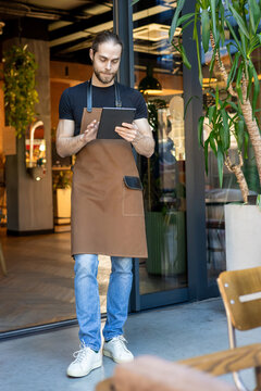 Professional waiter standing with tablet