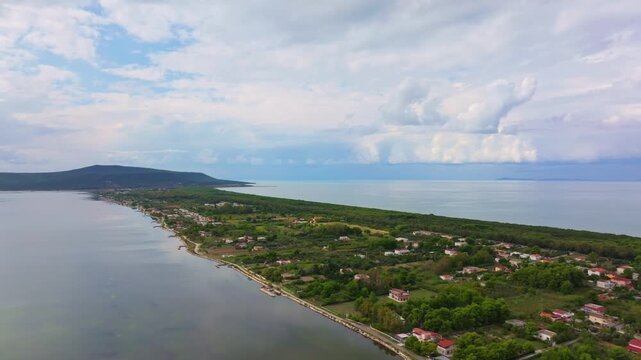 Aerial view of calm Lake Varano separated from the Adriatic Sea by a forested strip with tourist buildings and homes.