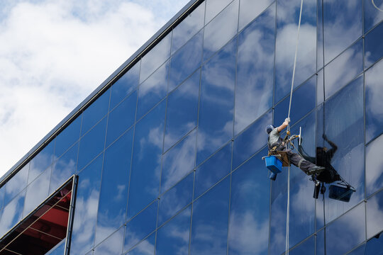 Industrial mountaineer cleaning glass office building