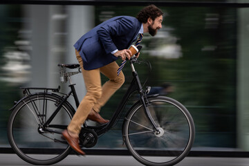 Fototapeta premium Business man rides bicycle fast in city