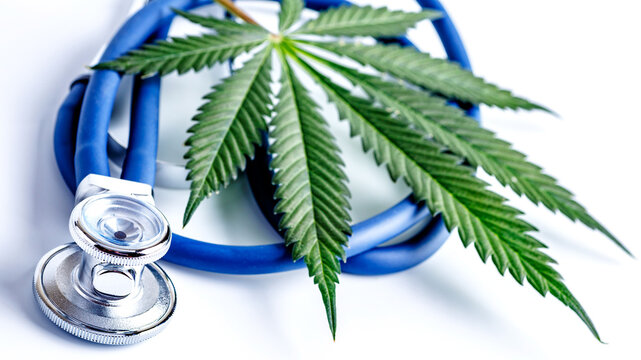 Medical marijuana and stethoscope. Green leaves of cannabis,pills and cbd oil over medical prescription sheet - medical marijuana concept.Selective Focus With Copy Space.