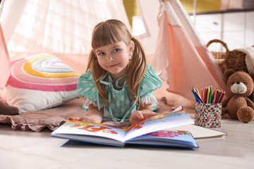 Little girl reading book in wigwam indoors © New Africa