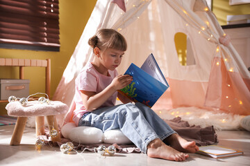 Little girl reading book in wigwam indoors © New Africa