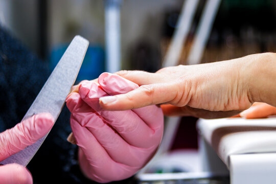 Manicurist filing nails of a client, providing professional hand and beauty care