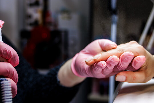 Manicurist sanitizing client's hand before nail treatment in a beauty salon