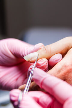 Manicurist working on a client's hand, performing cuticle treatment in a beauty salon