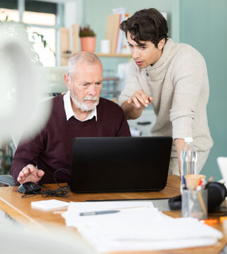 Guy help an older manager learn to use a laptop
