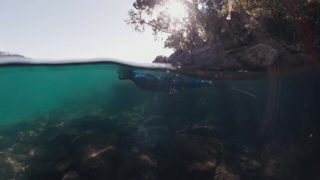 Freediving in Brazil, underwater camera. Woman freediver in the blue wetsuit swims in the sea near the island of Ilha Grande in Brazil