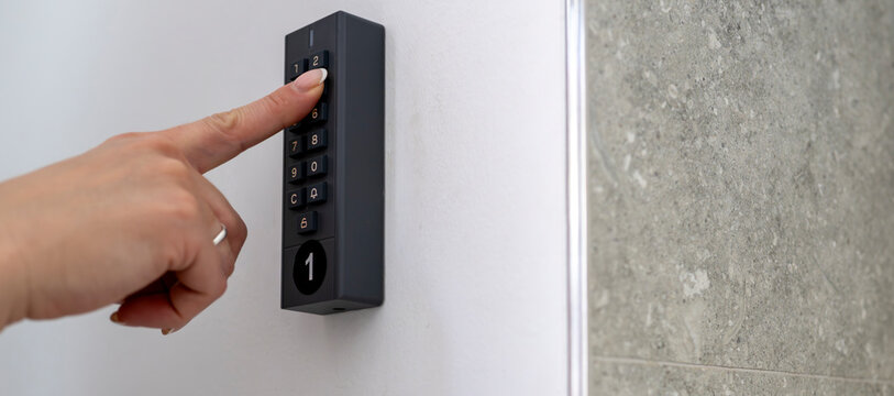 Woman using digital keypad lock for secure self check in at modern vacation apartment accommodation