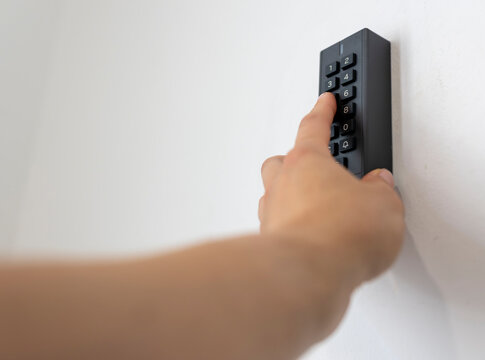 Hand entering temporary access code into secure smart lock system designed for autonomous guest arrivals