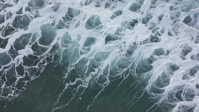 Aerial top down view of ocean waves breaking with white foam