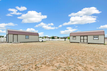 Naklejka premium Two storage sheds in open rural yard under blue sky