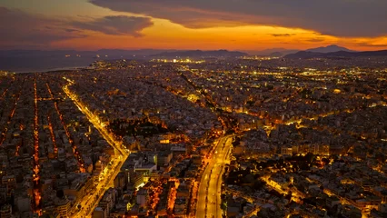 Fototapeten Mediterranes Europa Aerial view highlighting the sprawling urban landscape of athens, greece, with city lights brightly illuminating buildings, streets, and coastal areas during a vibrant twilight sunset  © Nasos Zovoilis