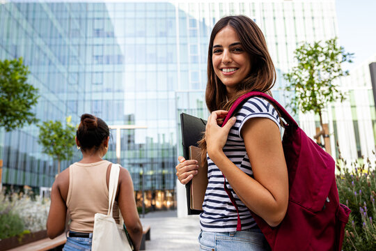 Happy student with backpack walking on university campus