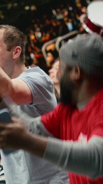 Vertical Video Excited diverse supporters jumping after winning live bet result, stadium crowd with adrenaline enjoying team victory.