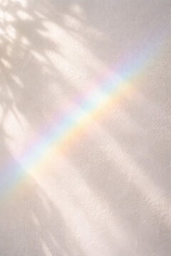 Soft pastel rainbow reflecting on a textured white wall