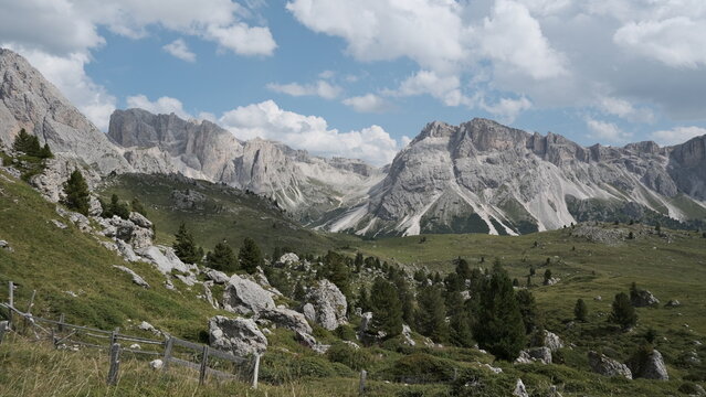 Tall isolated limestone rock spire beside hiking trail with Dolomite mountain range, Vallunga, South Tyrol, Italy