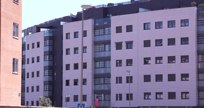 Static shot of a modern residential apartment building facade in Madrid, Spain. Repeating window arrangement and contrasting light and dark exterior panels create a geometric architectural pattern und