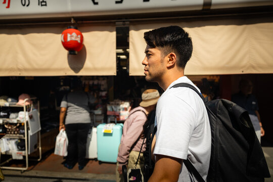 Young man passing a vibrant street market in Tokyo