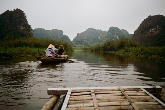 Travelers enjoy a boat ride on a river surrounded by mountains