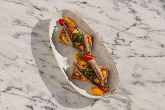 A serving of anchovy bruschetta paired with fresh tomatoes and herbs 