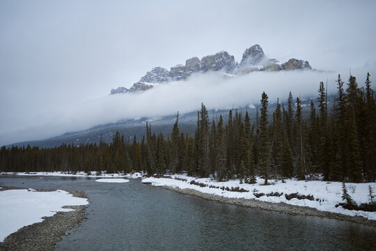 Snowy river flows through forest and mountains on a winter day