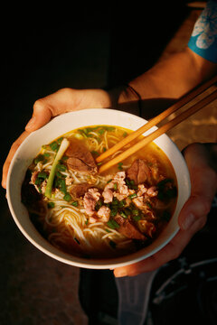 Enjoying a bowl of noodle soup with fresh ingredients in the evening